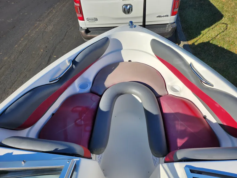Slide: The Image of 2003 Larson SEi 180 boat interior with red and gray seating, parked near a white truck. - 15
