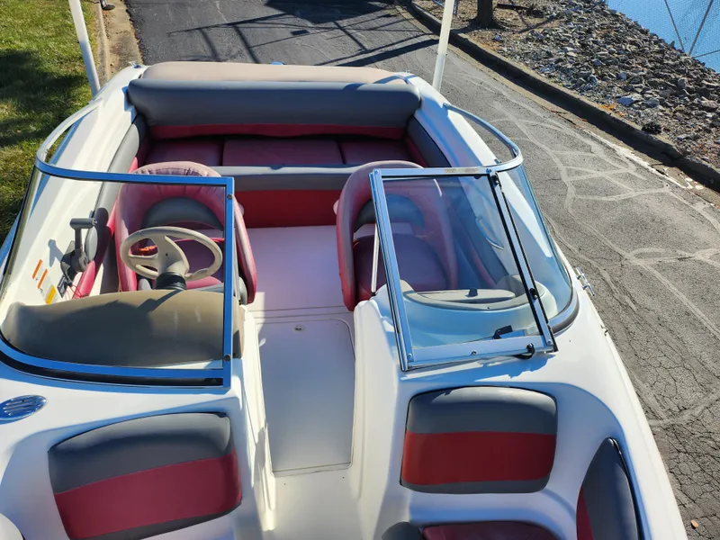Slide: The Image of 2003 Larson SEi 180 boat interior with red and gray seating, docked by the water. - 17