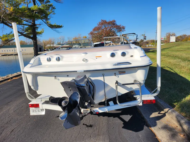 Slide: The Image of 2003 Larson SEi 180 boat on trailer, rear view, parked near a lake. - 2