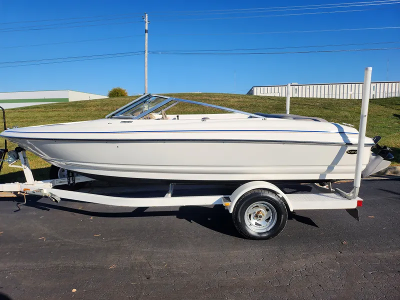 Slide: The Image of 2003 Larson SEi 180 boat on trailer, parked outdoors under clear blue sky. - 4