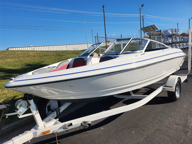 Slide: The Image of 2003 Larson SEi 180 boat on trailer, white with blue trim, parked outdoors. - 5