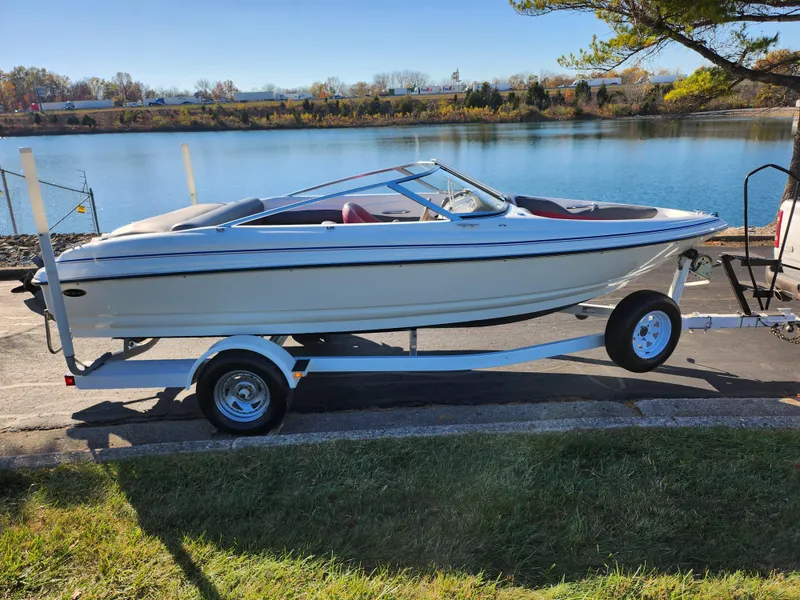 Slide: The Image of 2003 Larson SEi 180 boat on trailer by a lake. - 9