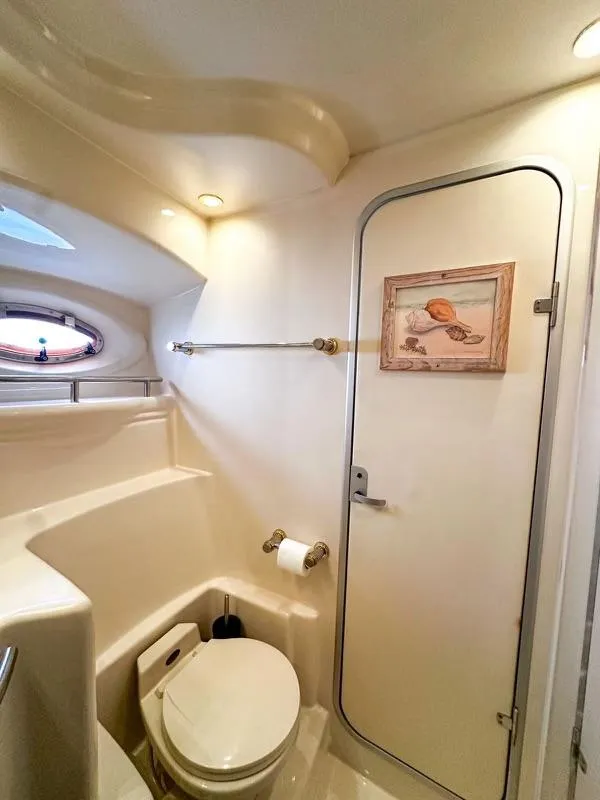 Slide: The Image of 1999 Maxum 4100 SCR yacht bathroom with toilet, porthole, and seashell artwork. - 19