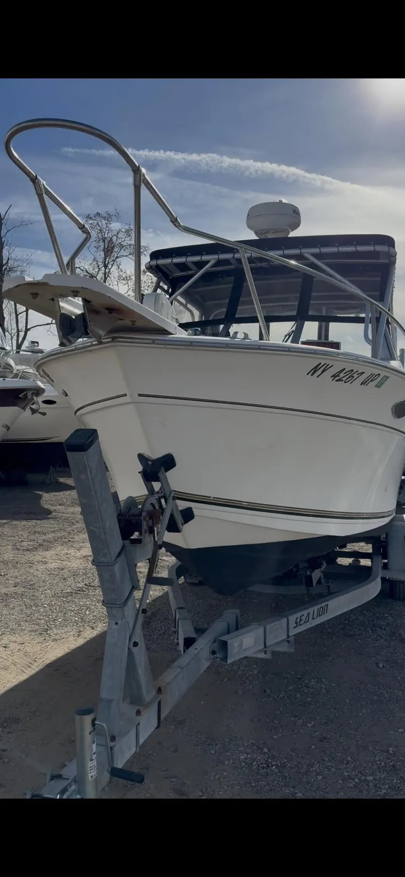 The Image of 1998 Sport-Craft 252 Sportfish boat on trailer, parked outdoors under clear sky. - 0