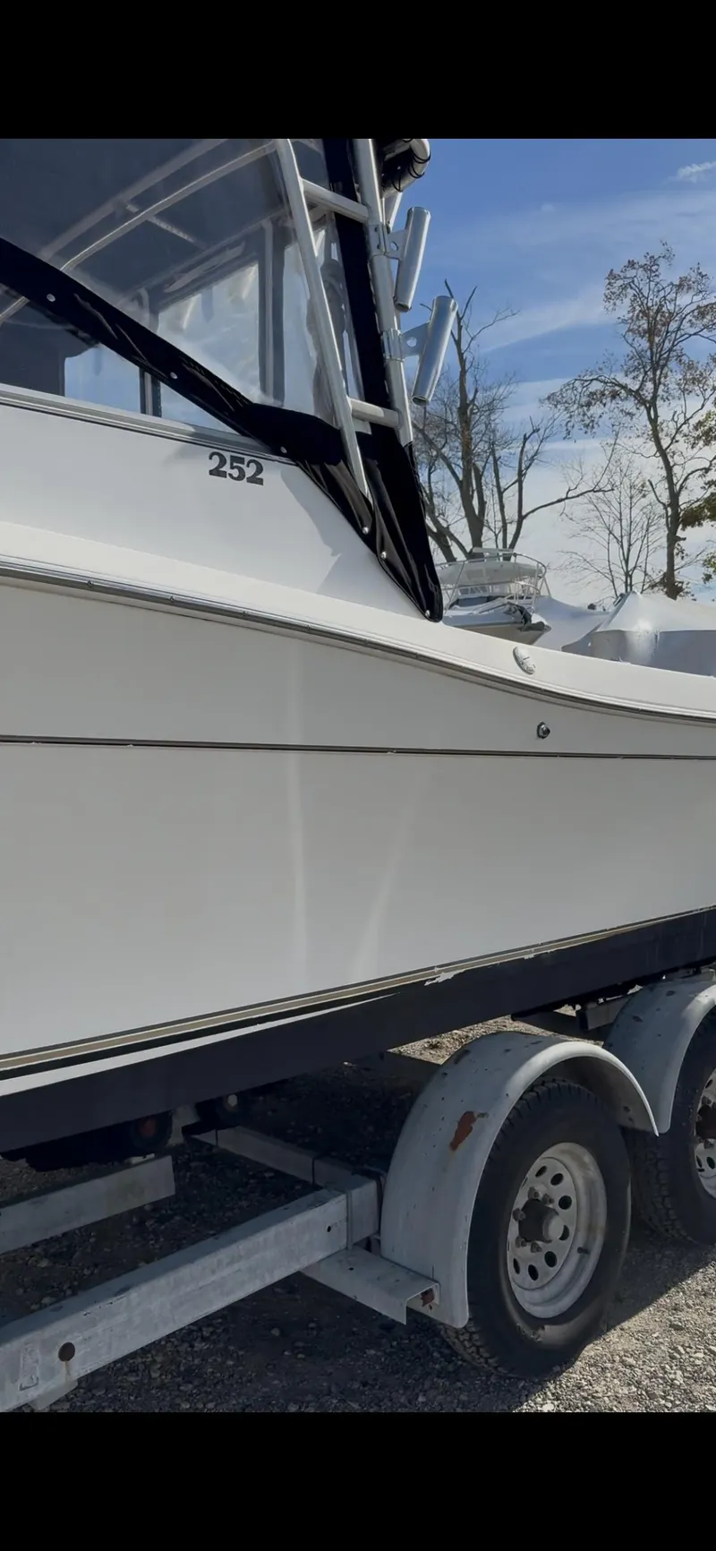 Slide: The Image of 1998 Sport-Craft 252 Sportfish boat with outboard motor, parked on pavement. - 2