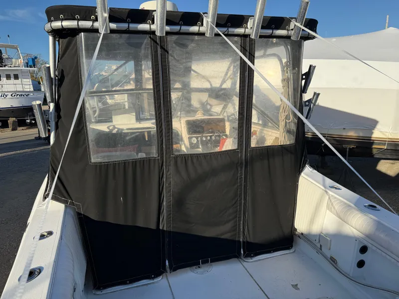 Slide: The Image of 1998 Sport-Craft 252 Sportfish boat on trailer, parked near marina under blue sky. - 5