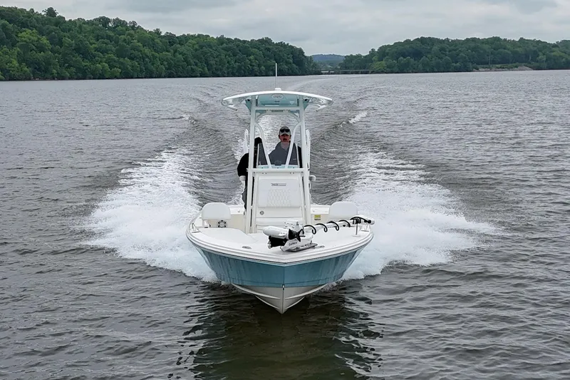 Slide: The Image of 2025 Pathfinder 2200 TRS boat cruising on a lake with lush green shoreline. - 36