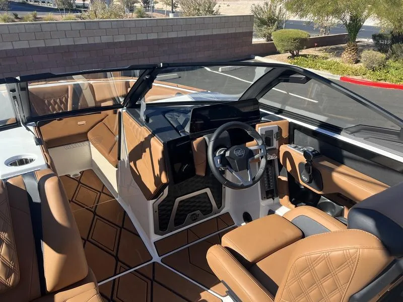 Slide: The Image of 2025 Malibu M230 boat interior with luxurious brown leather seating and modern dashboard. - 11