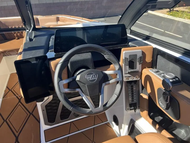 Slide: The Image of 2025 Malibu M230 boat interior with modern steering wheel and dashboard controls. - 12