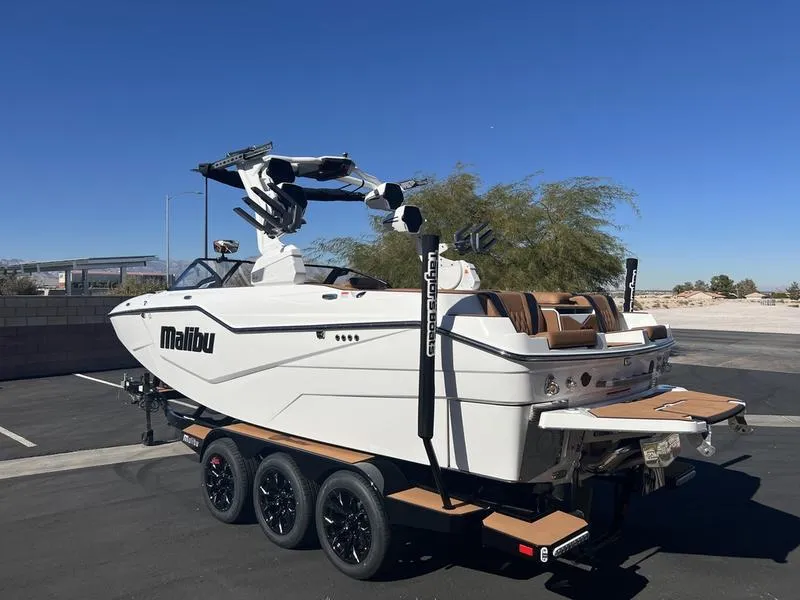 Slide: The Image of 2025 Malibu M230 boat on trailer, sleek design, white exterior, sunny day. - 4