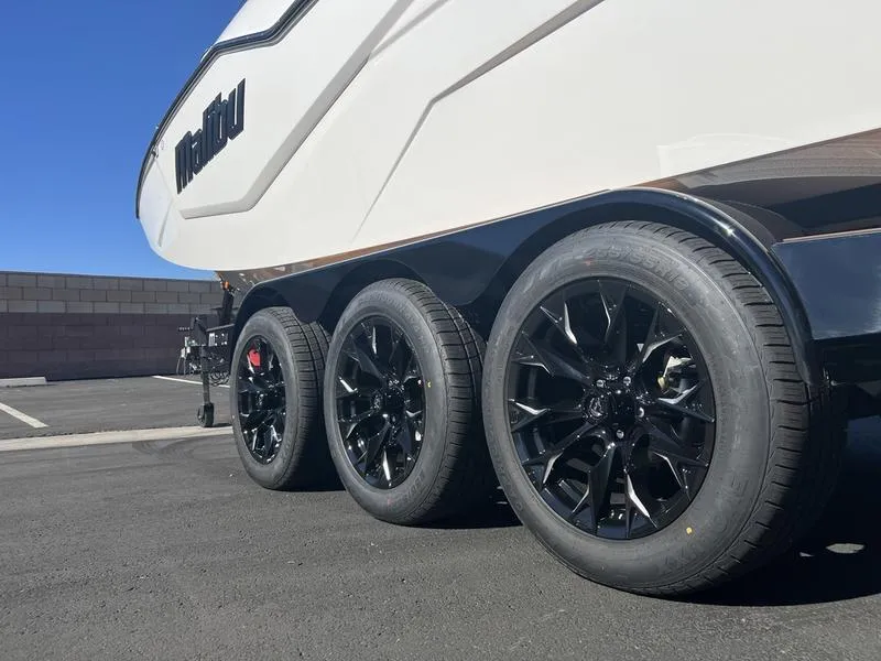 Slide: The Image of 2025 Malibu M230 boat trailer with sleek black wheels in a parking lot. - 7