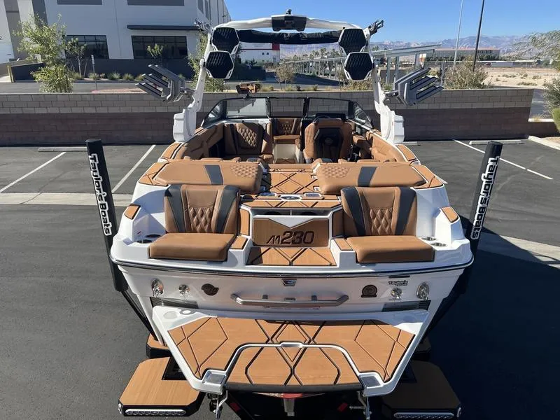 Slide: The Image of 2025 Malibu M230 boat with luxurious seating and modern design in a parking lot. - 9