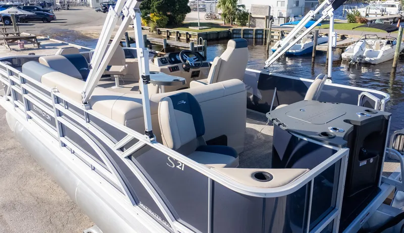 Slide: The Image of 2025 Bennington 21SF pontoon boat with spacious seating and modern amenities at a marina. - 5