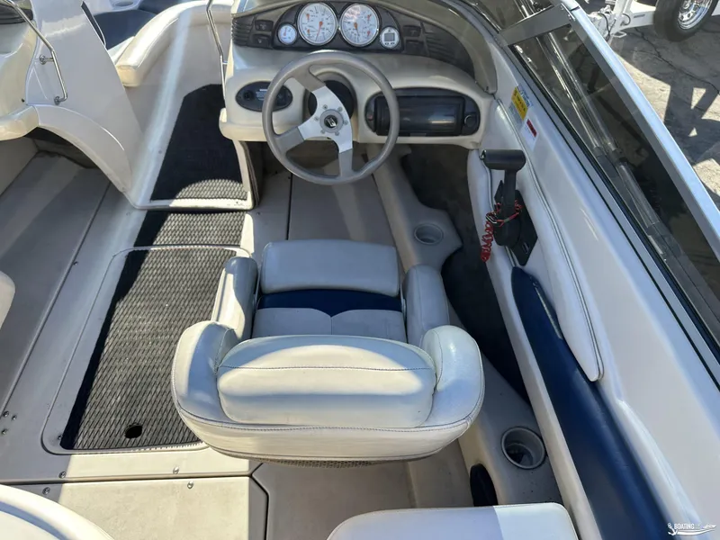 Slide: The Image of Interior of a 2002 Larson 210 SEI boat, featuring steering wheel and seating. - 10