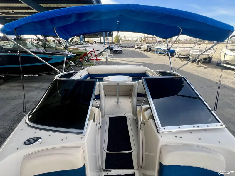 Slide: The Image of 2002 Larson 210 SEI boat with blue canopy and spacious seating. - 2