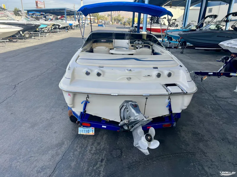 Slide: The Image of 2002 Larson 210 SEI boat with blue canopy in a marina. - 3