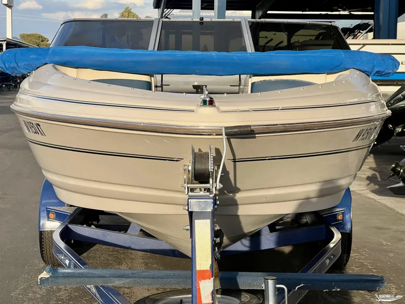 Slide: The Image of 2002 Larson 210 SEI boat on trailer with blue cover, parked outdoors. - 4