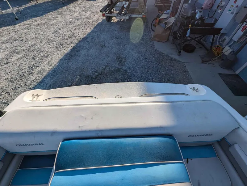 Slide: The Image of 1992 Chaparral 1900 SL boat interior with blue and white seating, parked on gravel. - 10