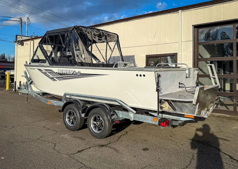 Slide: The Image of 2025 Hewescraft 210 Sea Runner ET boat on trailer, parked outside a building. - 3