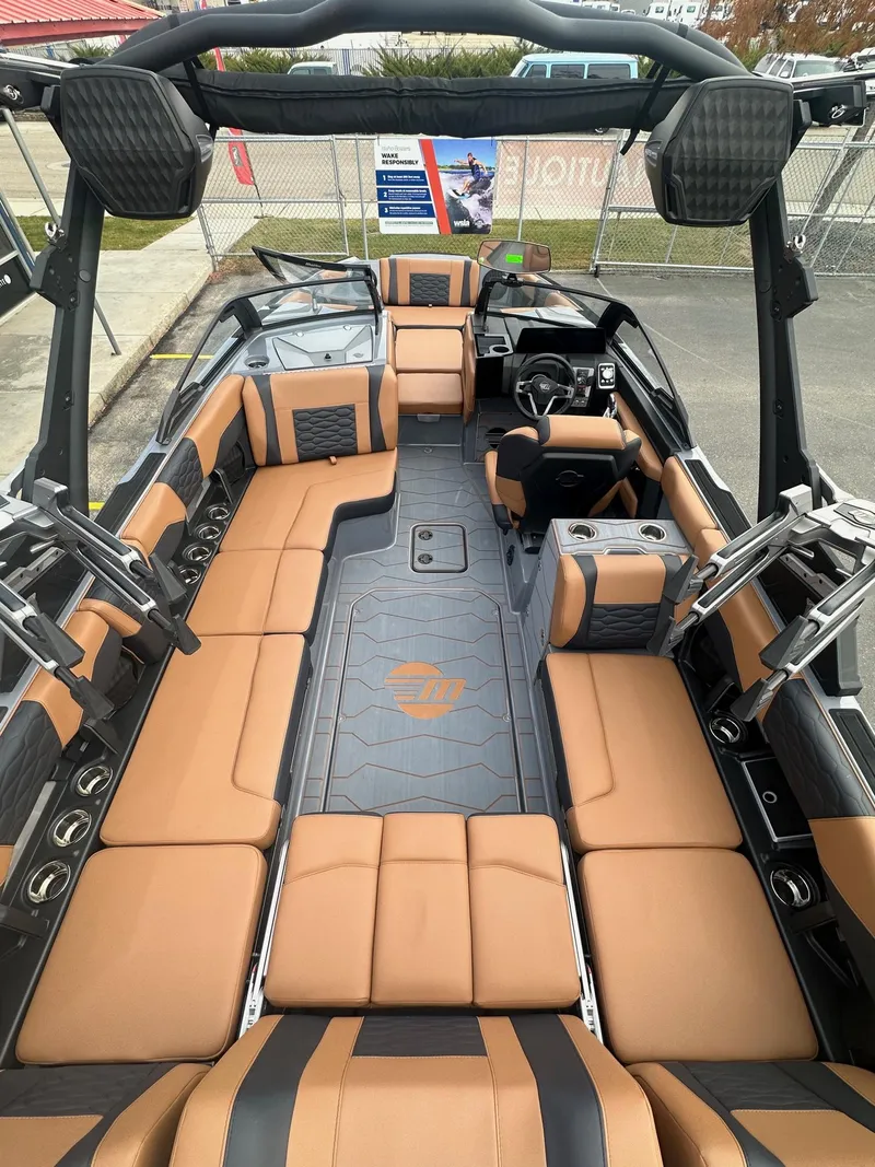 Slide: The Image of 2025 Malibu 24 MXZ boat interior with tan and black seating, spacious layout. - 11