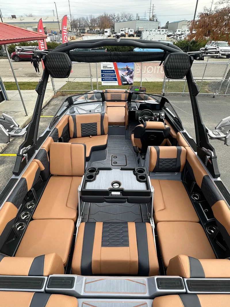Slide: The Image of 2025 Malibu 24 MXZ boat interior with tan and black seating, spacious layout, and modern design. - 12