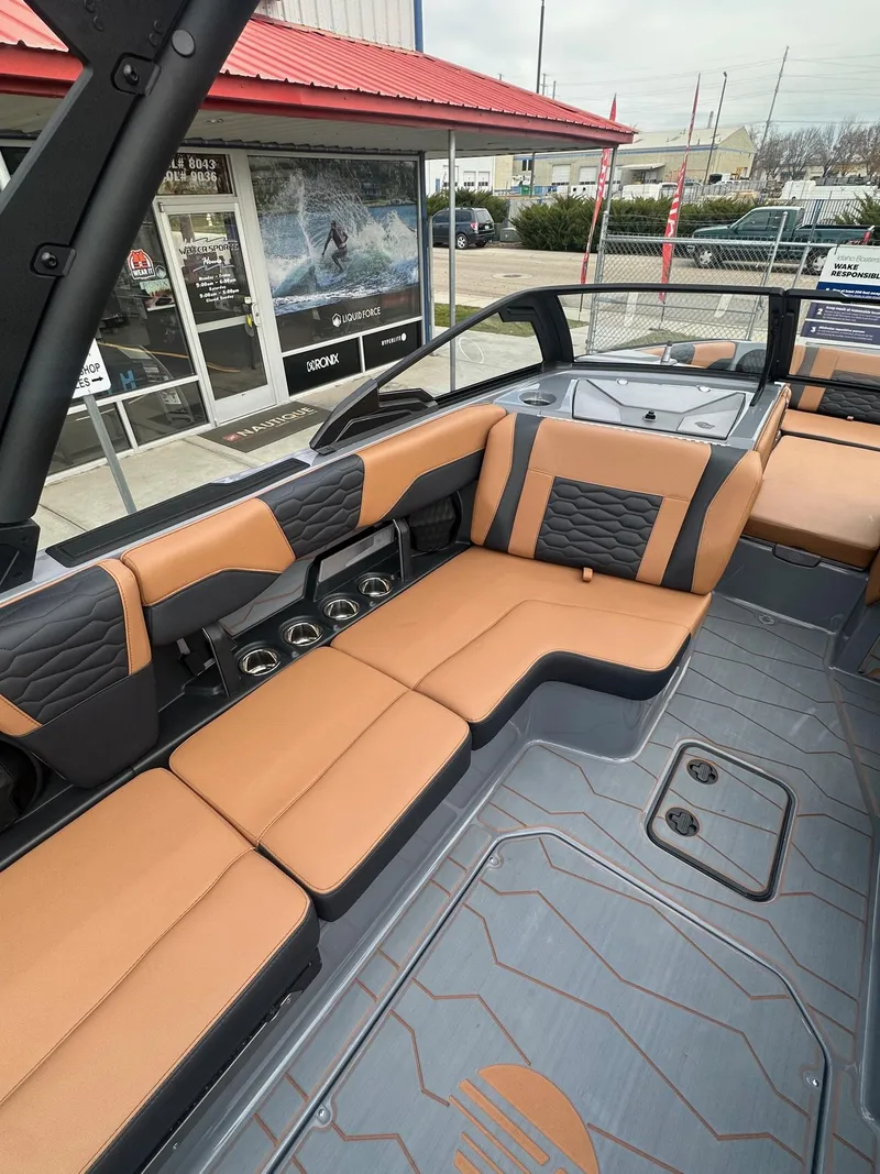 Slide: The Image of 2025 Malibu 24 MXZ boat interior with tan and black seating, modern design. - 17