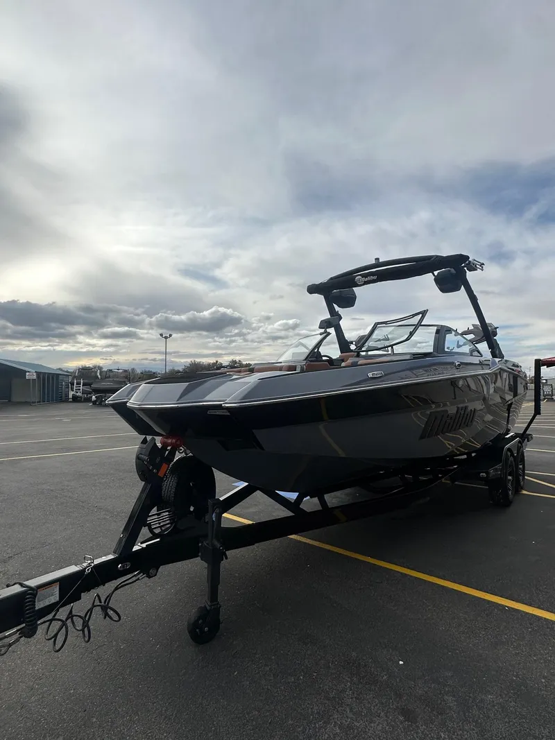Slide: The Image of 2025 Malibu 24 MXZ boat on trailer under cloudy sky. - 6