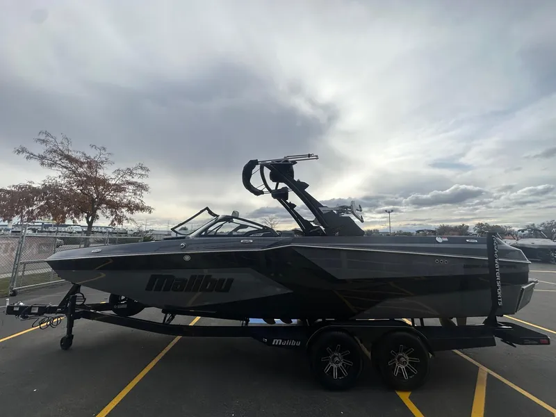 Slide: The Image of 2025 Malibu 24 MXZ boat on trailer under cloudy sky. - 7
