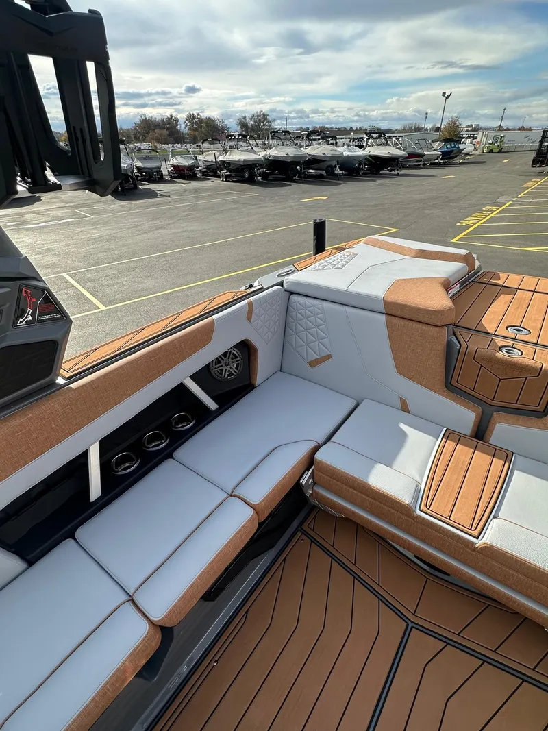Slide: The Image of 2025 Nautique GS22 boat interior with tan and white seating, parked in a marina. - 15
