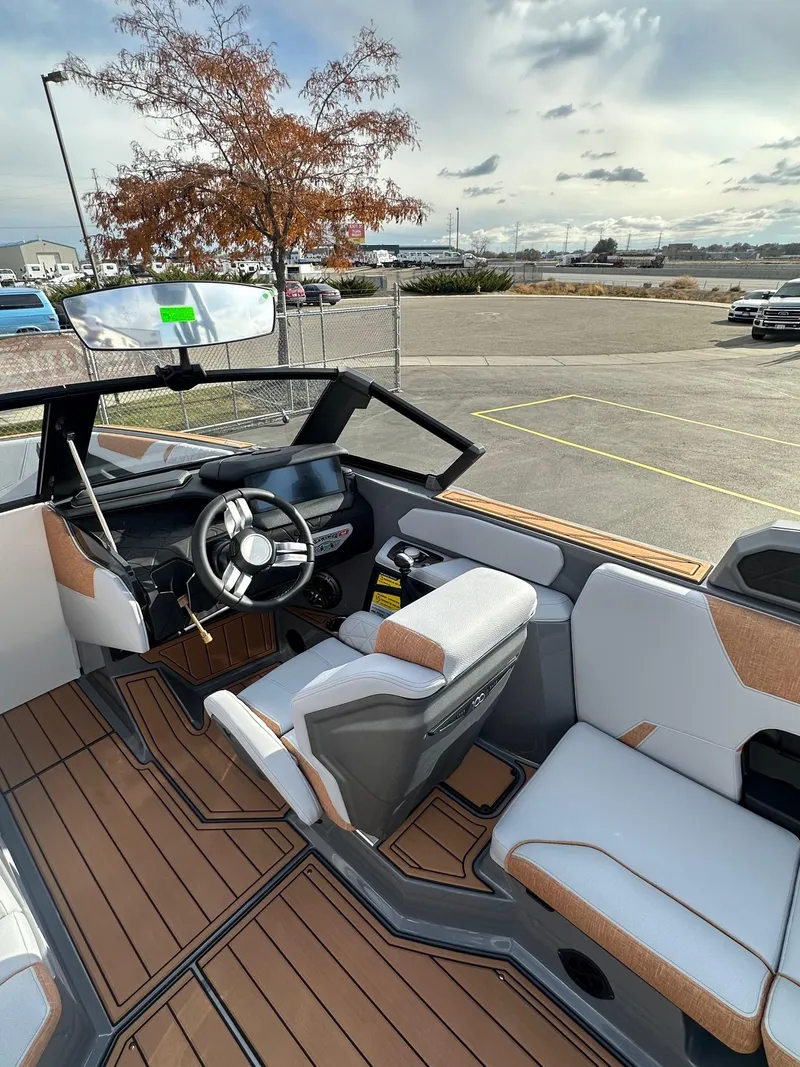 Slide: The Image of 2025 Nautique GS22 boat interior with modern steering and seating, parked outdoors. - 18