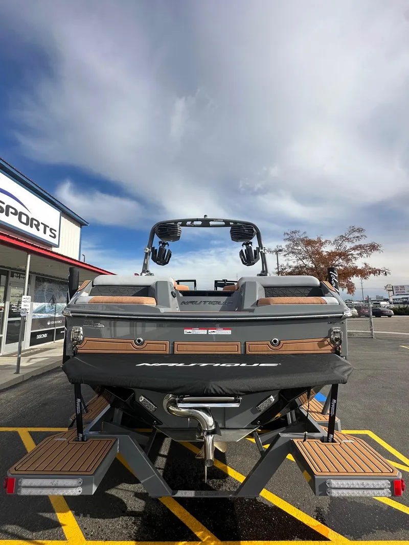Slide: The Image of 2025 Nautique GS22 boat, rear view, parked outside dealership under cloudy sky. - 9