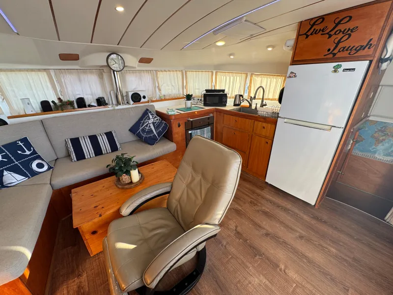 Slide: The Image of Interior of 2001 Lagoon 410 catamaran with cozy seating and kitchen area. - 30