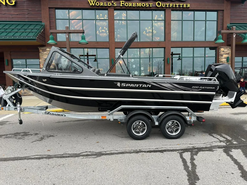 Slide: The Image of 2025 Spartan 200 Astoria boat on trailer outside outdoor outfitter store. - 2