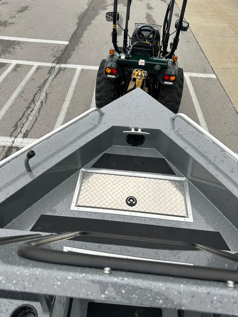Slide: The Image of 2025 Spartan 200 Astoria boat on trailer, parked in lot with tractor. - 20