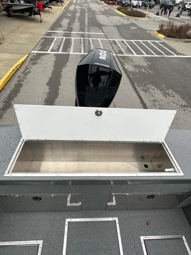 Slide: The Image of 2025 Spartan 200 Astoria boat with open storage compartment and outboard motor. - 21