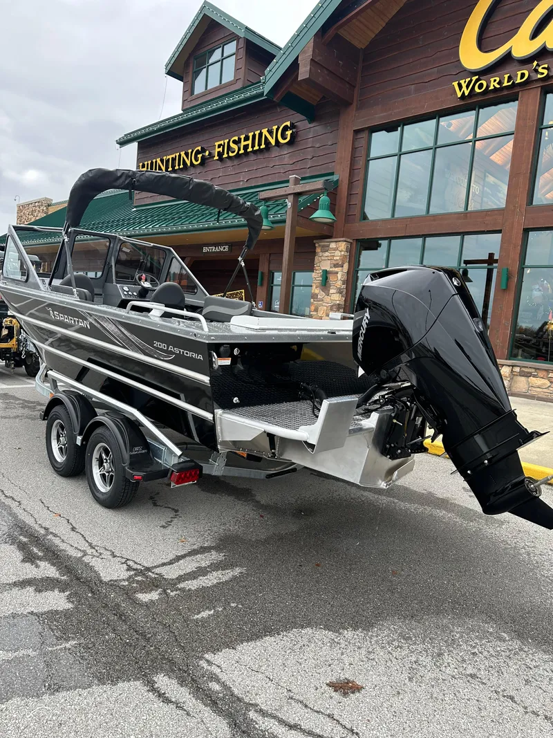 Slide: The Image of 2025 Spartan 200 Astoria boat on trailer outside hunting and fishing store. - 3