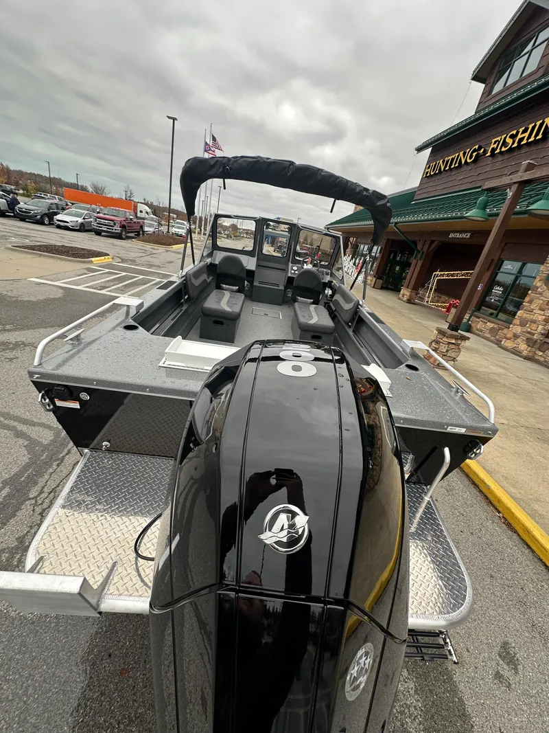 Slide: The Image of 2025 Spartan 200 Astoria boat with powerful outboard motor, parked near a fishing store. - 8