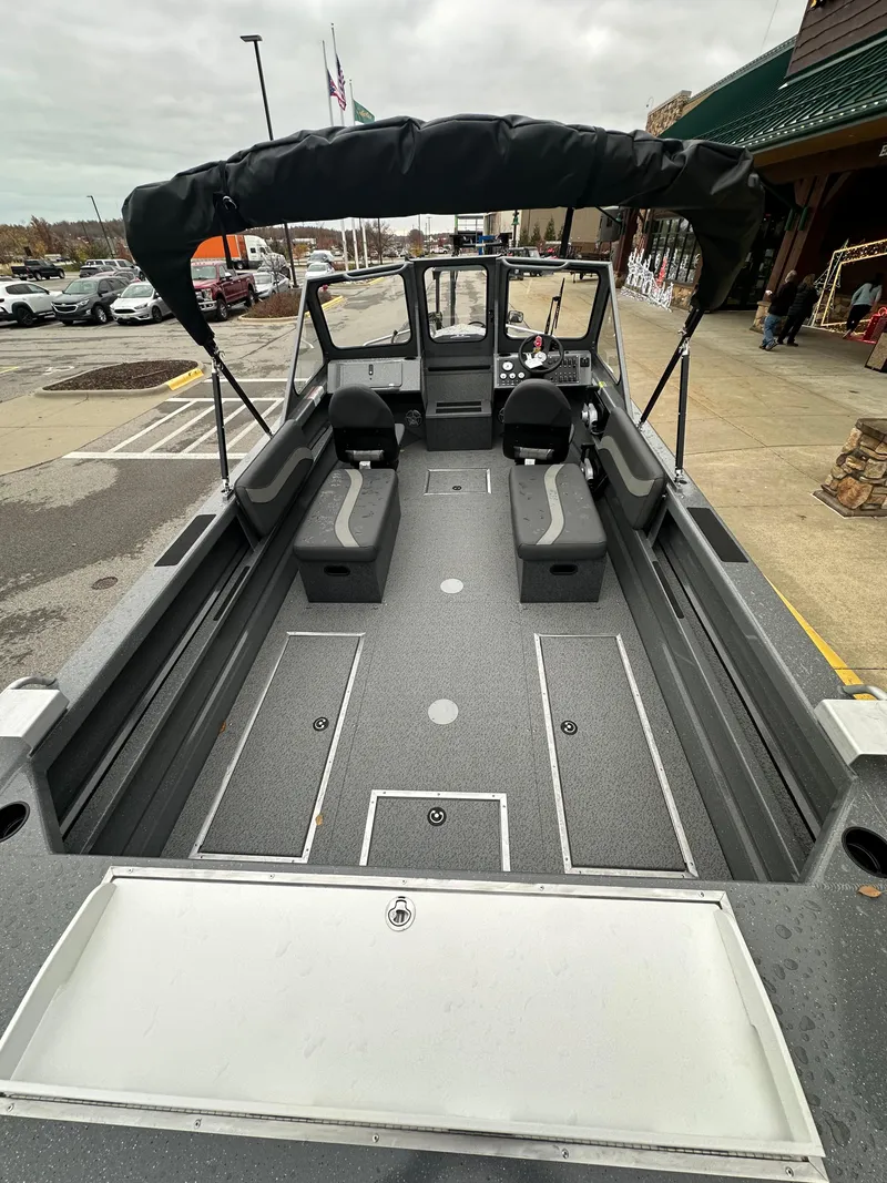 Slide: The Image of 2025 Spartan 200 Astoria boat with spacious interior and canopy, parked outdoors. - 9