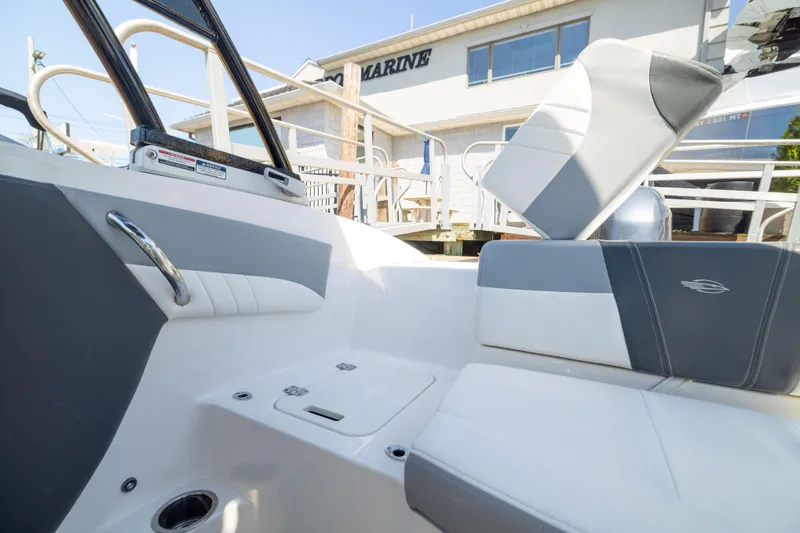 Slide: The Image of 2022 Chaparral 21 SSi OB boat interior with gray and white seating, docked at a marina. - 10