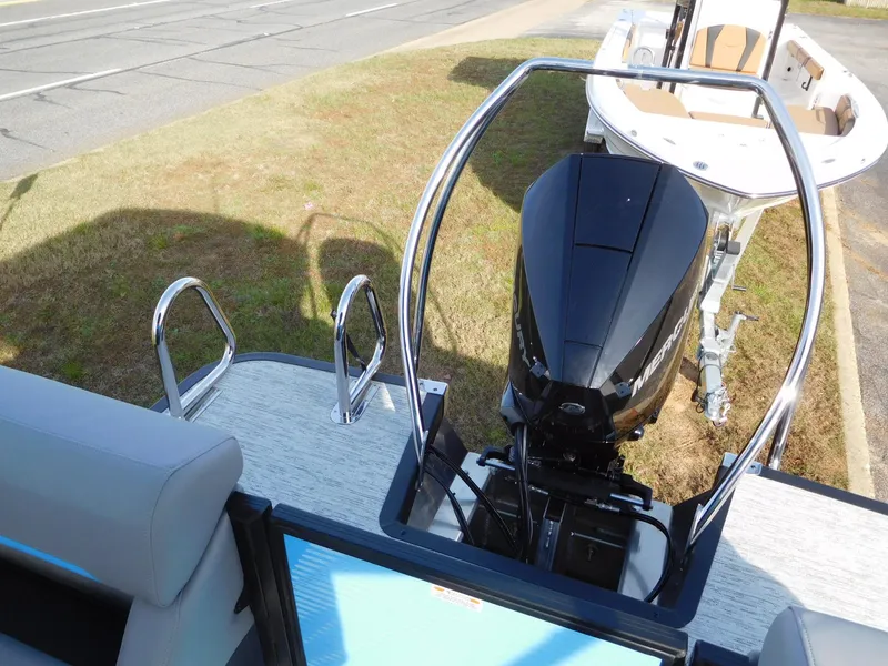 Slide: The Image of 2025 Bennington 24 MFB boat with powerful outboard motor, parked on grass. - 13