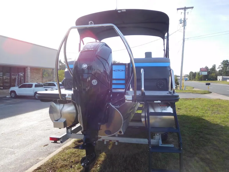 Slide: The Image of 2025 Bennington 24 MFB boat with outboard motor, parked outdoors. - 14