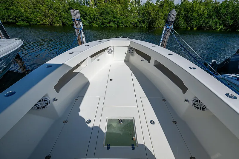 Slide: The Image of 2018 SeaVee 370z boat deck with spacious seating and storage, docked by lush greenery. - 32