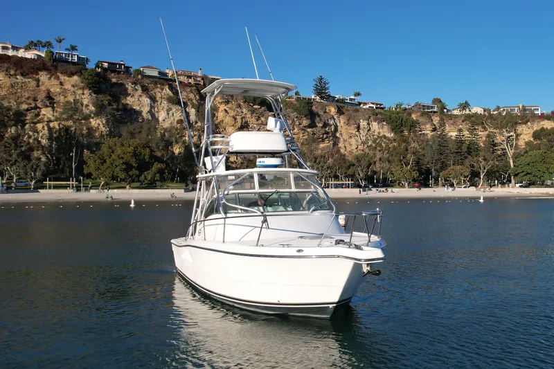 Slide: The Image of 2006 Rampage 30 Offshore boat on calm water near a scenic cliffside. - 6