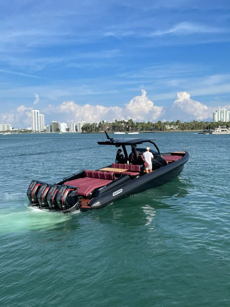 Slide: The Image of 2023 Skipper-BSK 42 luxury boat cruising on a sunny day near a city skyline. - 13