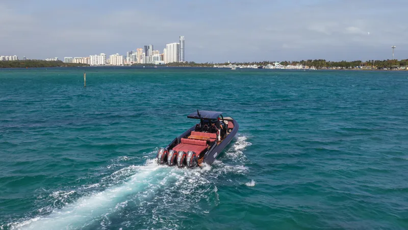 Slide: The Image of Skipper-BSK 42 boat cruising in turquoise waters, city skyline in background, 2023 model. - 9