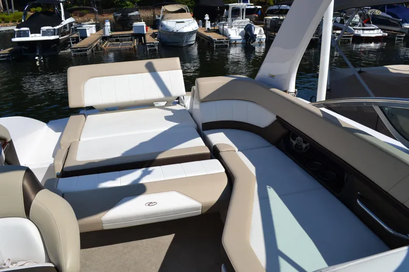 Slide: The Image of 2013 Regal 24 FasDeck boat interior with beige and white seating at a marina. - 18
