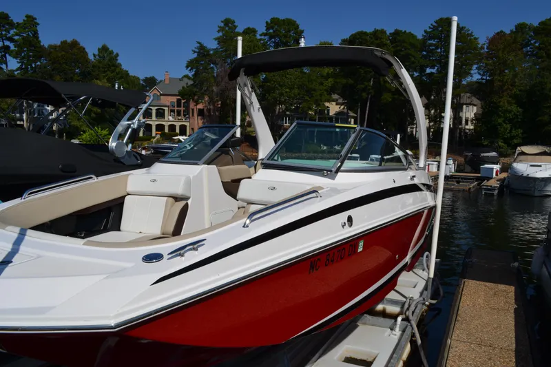 Slide: The Image of 2013 Regal 24 FasDeck boat with red hull, docked at a marina. - 2