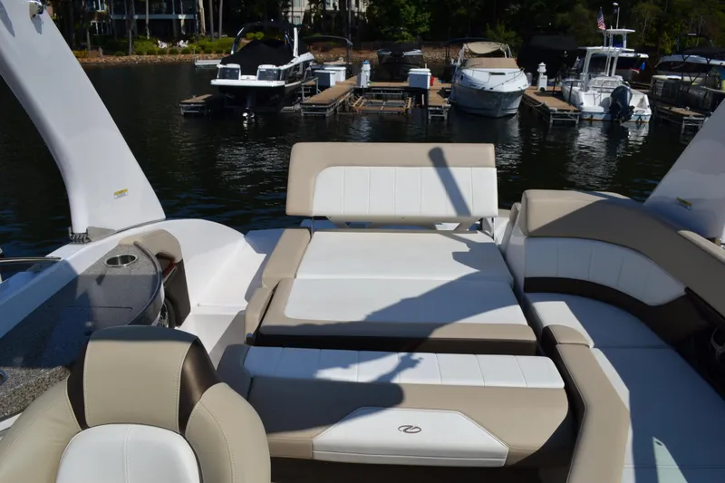 Slide: The Image of 2013 Regal 24 FasDeck boat interior with beige and white seating at a marina. - 22