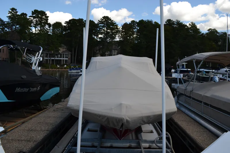 Slide: The Image of 2013 Regal 24 FasDeck boat covered at dock, surrounded by trees and other boats. - 4
