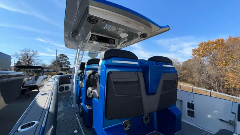 Slide: The Image of 2021 Fountain 34 SC boat with blue seating and canopy, docked outdoors. - 44